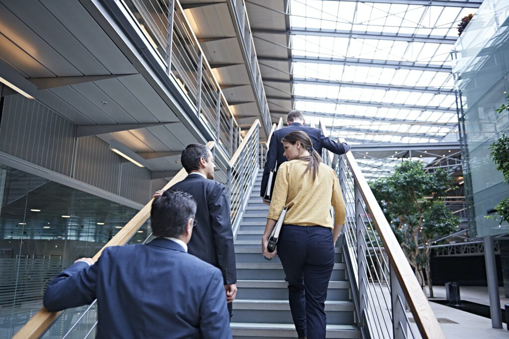 Rear view of businesswoman and men moving up office stairway